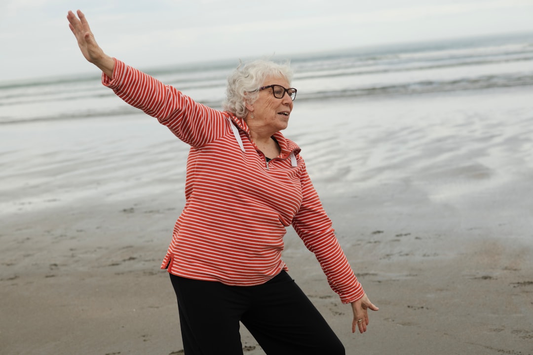 Older woman practicing tai chi outdoors, balancing on one leg