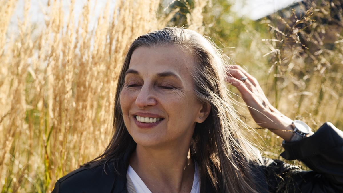 Smiling woman with silver-streaked hair in golden sunlight