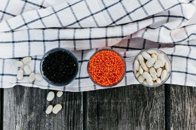 Bowls of black beans, red lentils and white beans on a kitchen towel