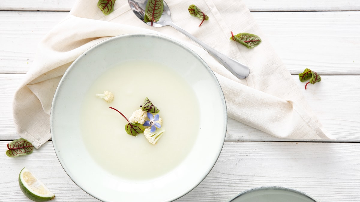 White creamy bowl with herbs on a white wooden table