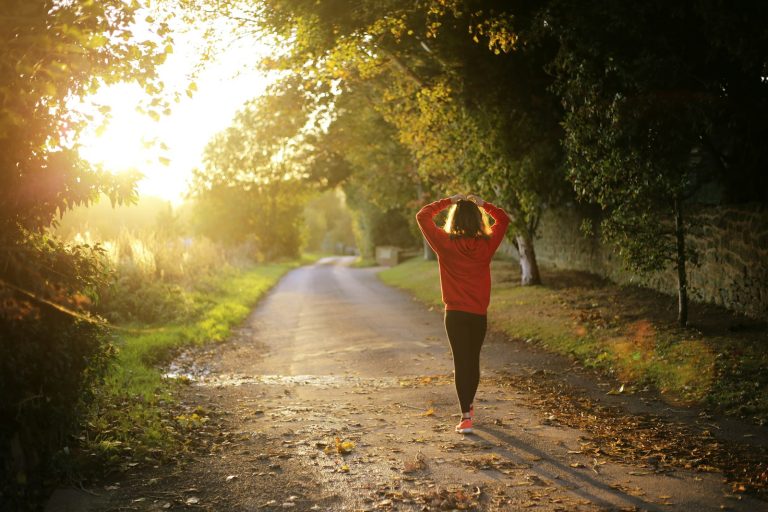 Woman walking down a sunlit country lane in the evening