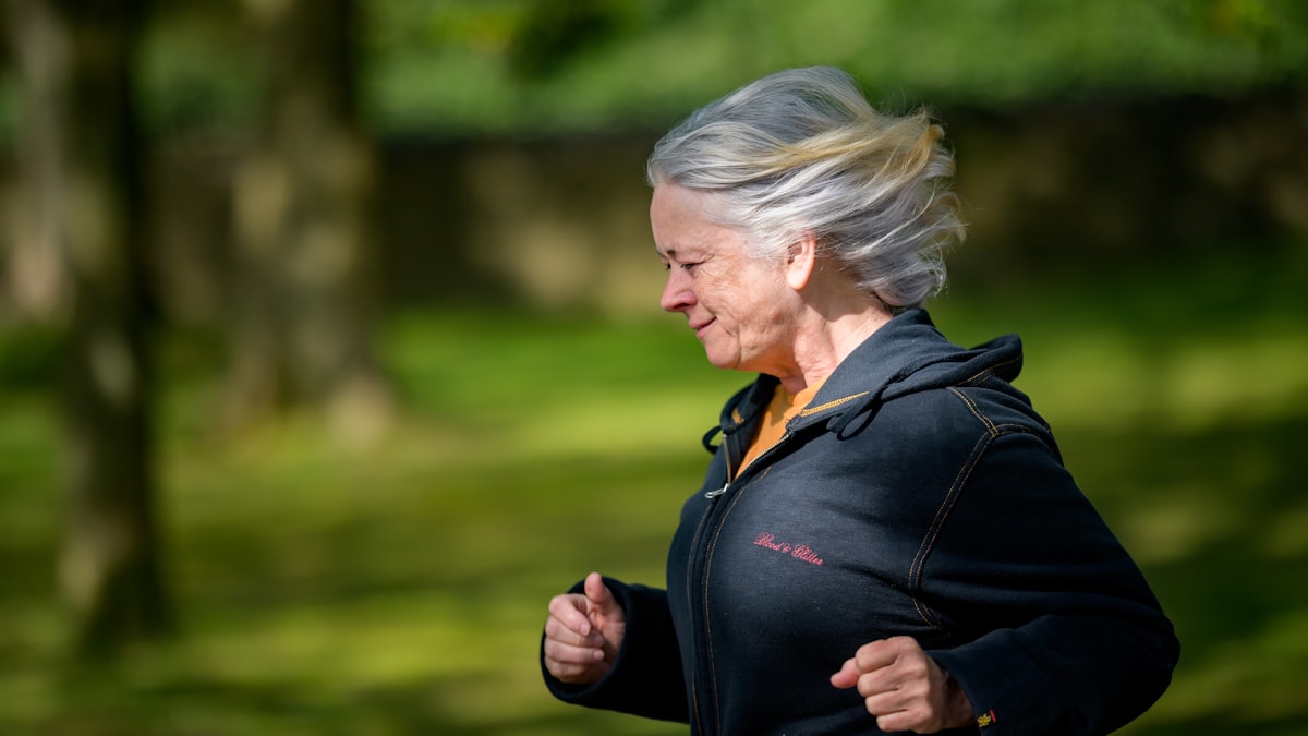 Silver-haired woman jogging energetically through a park