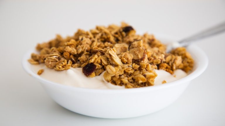 Bowl of yogurt topped with granola on a white table