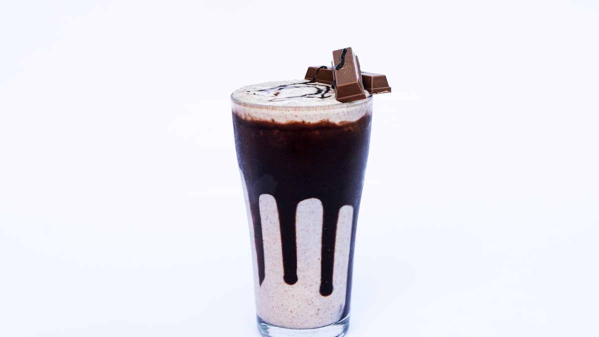 Chocolate protein smoothie in a glass topped with chocolate pieces