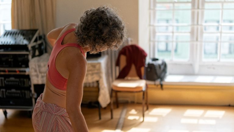 Gray-haired woman exercising in a bright room