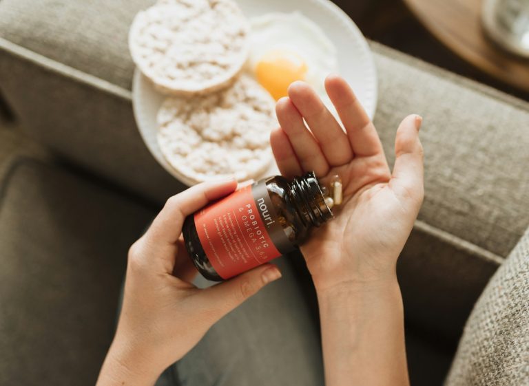 Woman shaking supplement capsules into her hand at breakfast