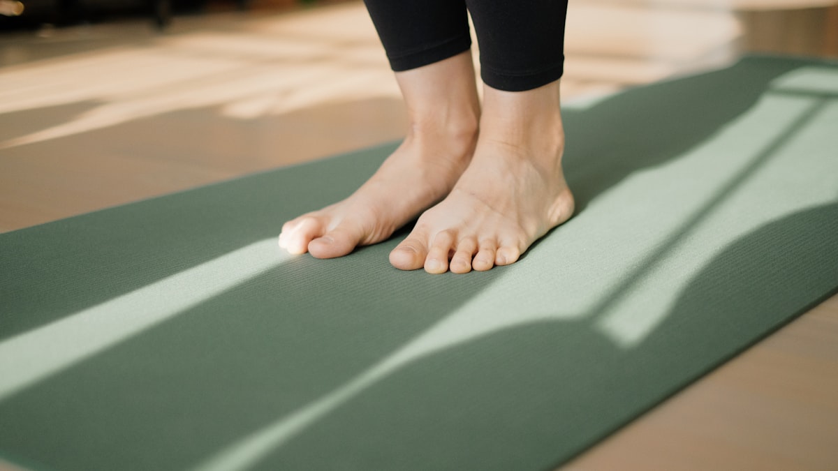 Bare feet on a green exercise mat in sunlight
