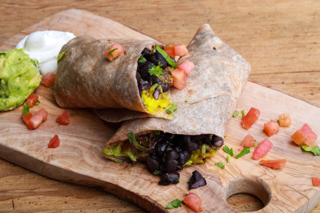 Whole wheat breakfast burrito cut open to show black beans, eggs, and tomato