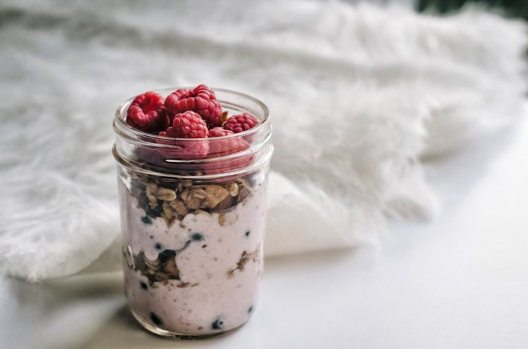 Overnight oats in a mason jar layered with granola and raspberries
