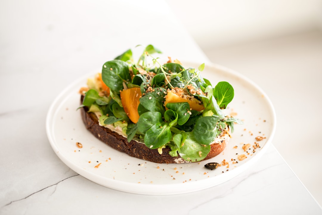 Open-faced toast piled with greens and vegetables on a white plate