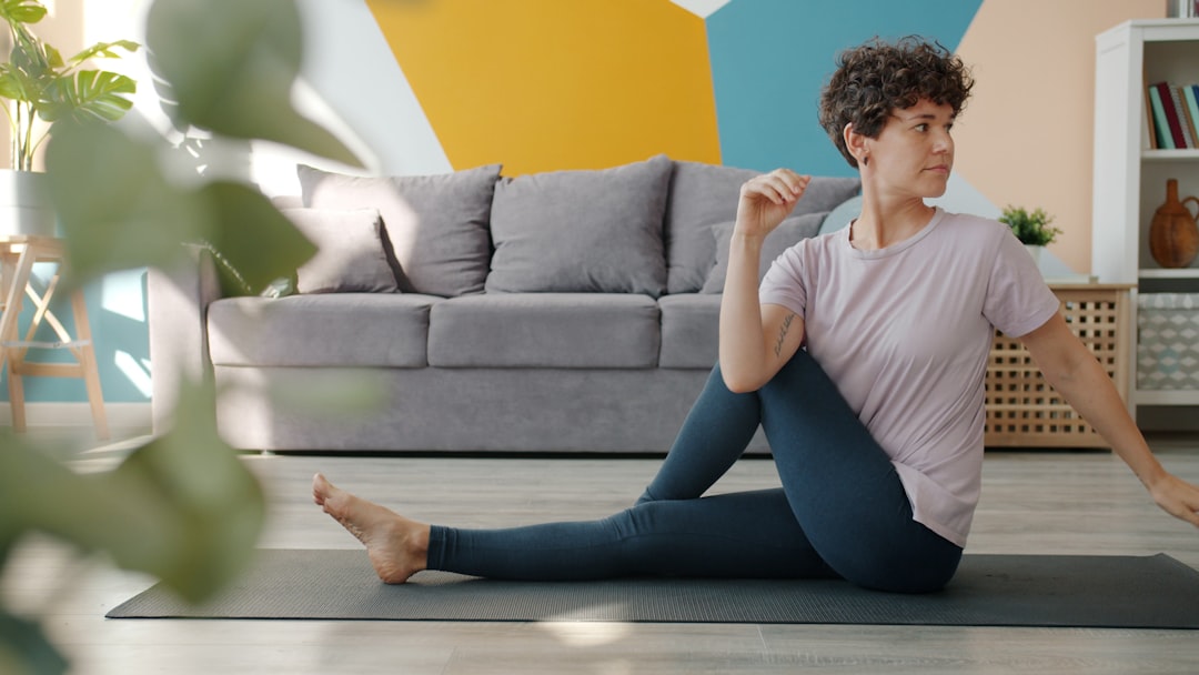 Woman doing a gentle seated spinal twist on a mat in her living room