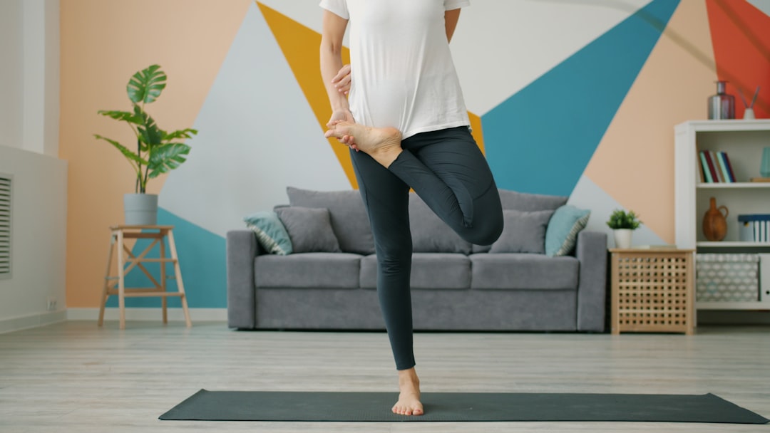 Woman balancing on one leg in tree pose on an exercise mat at home