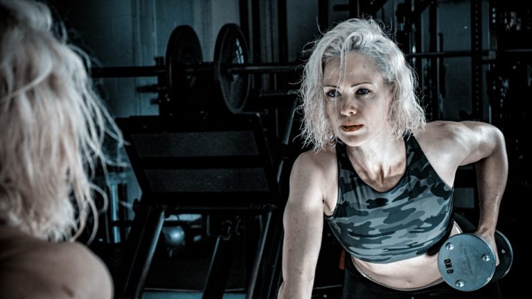 Woman with grey hair lifting a dumbbell in a gym