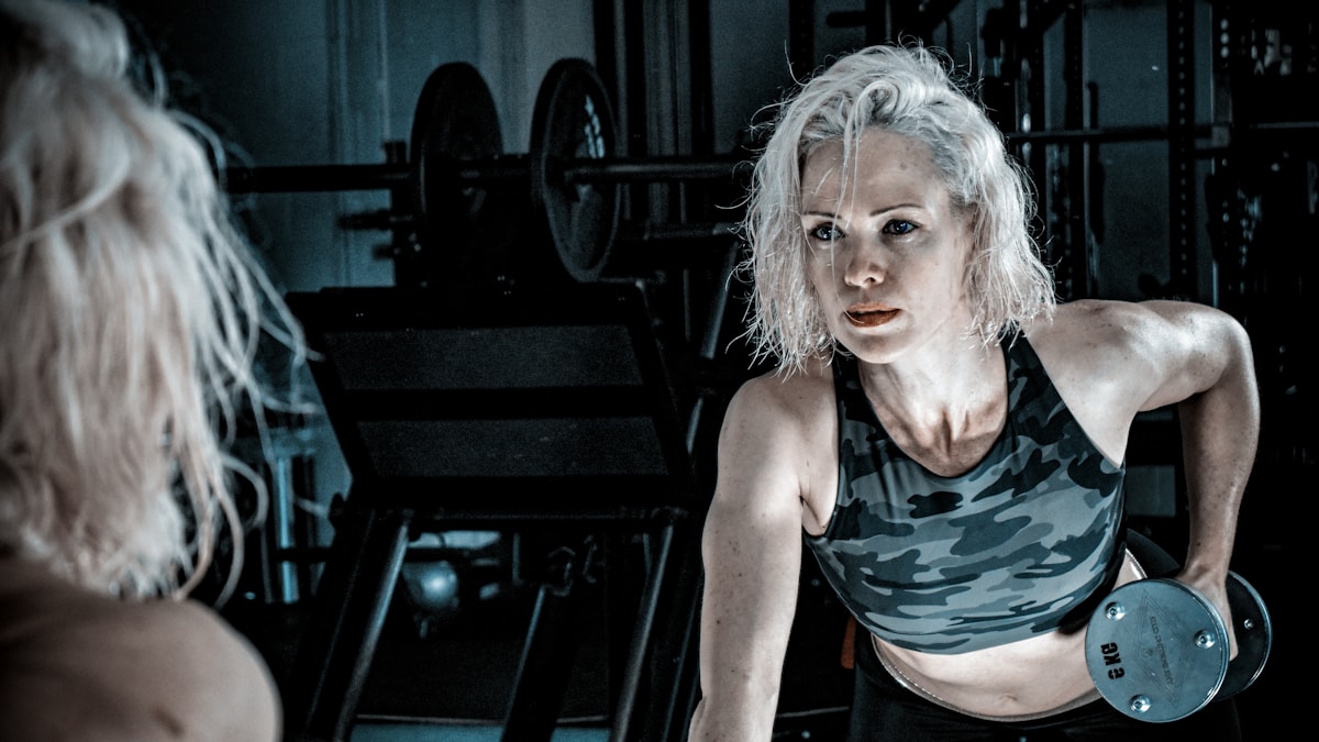 Woman with grey hair lifting a dumbbell in a gym