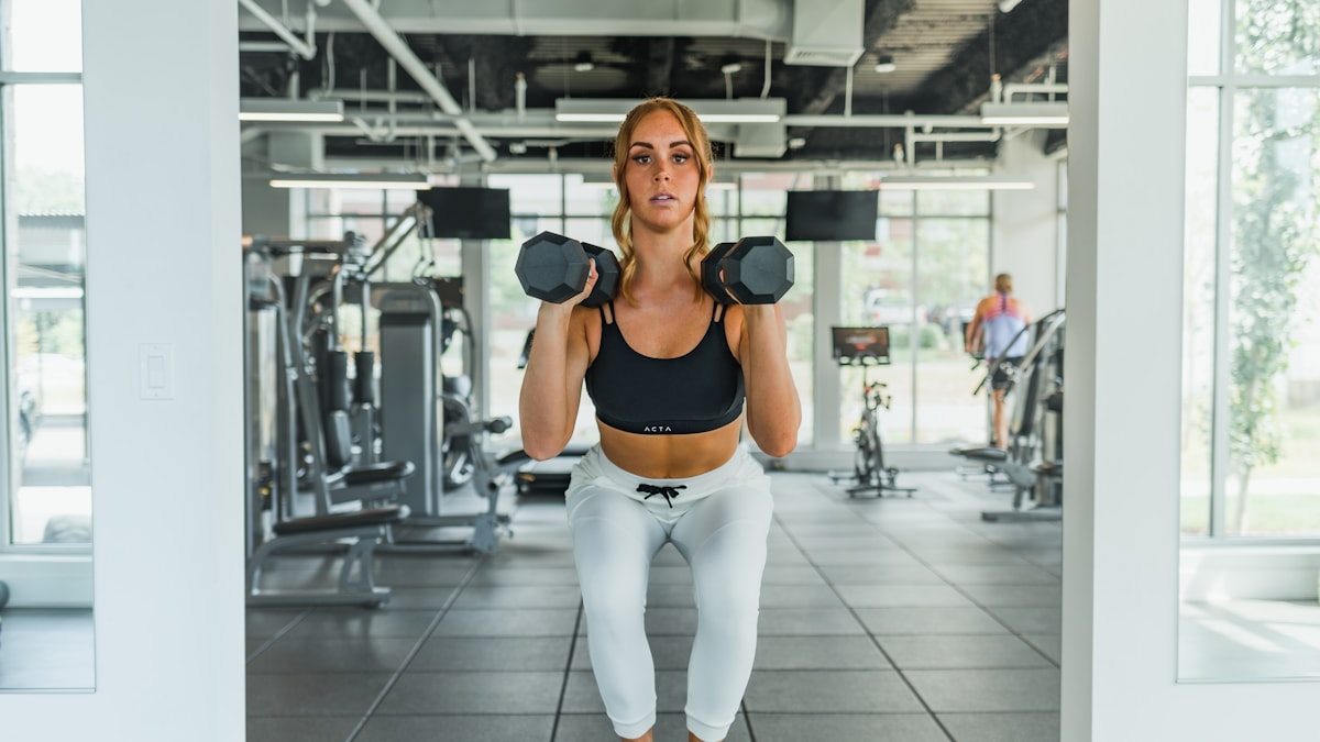 Woman standing on a low box holding a pair of dumbbells
