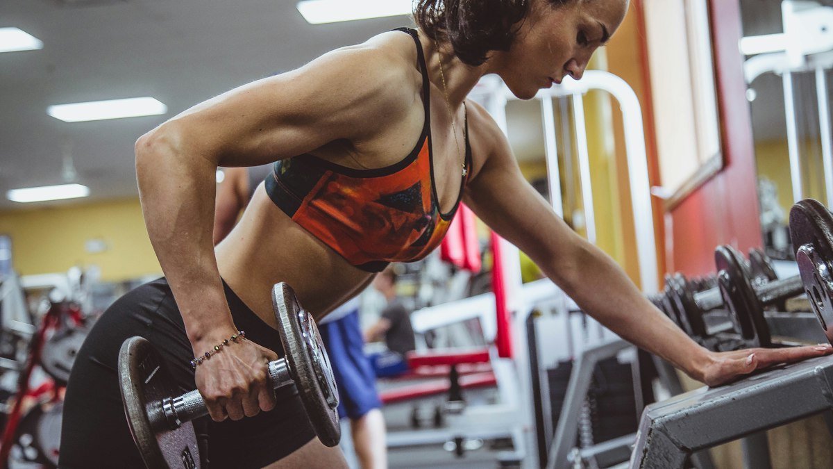A woman performing a dumbbell row in a gym