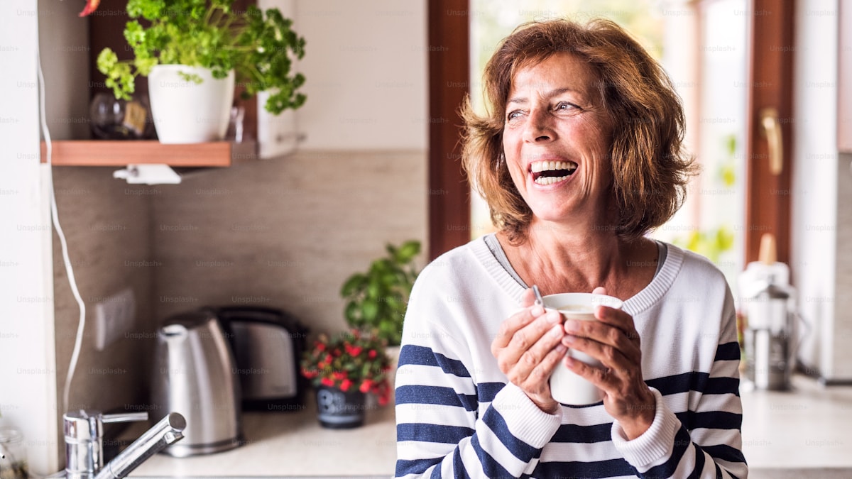 Smiling woman in a striped top holding a mug in her kitchen