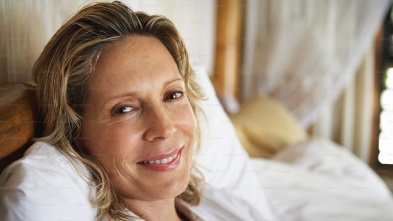 Woman lying in bed smiling at the camera