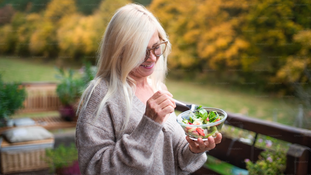 Woman on a terrace eating a bowl of salad