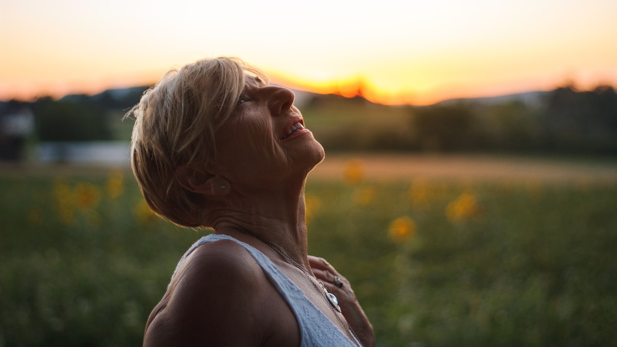 Woman with eyes closed facing the sunrise in a field