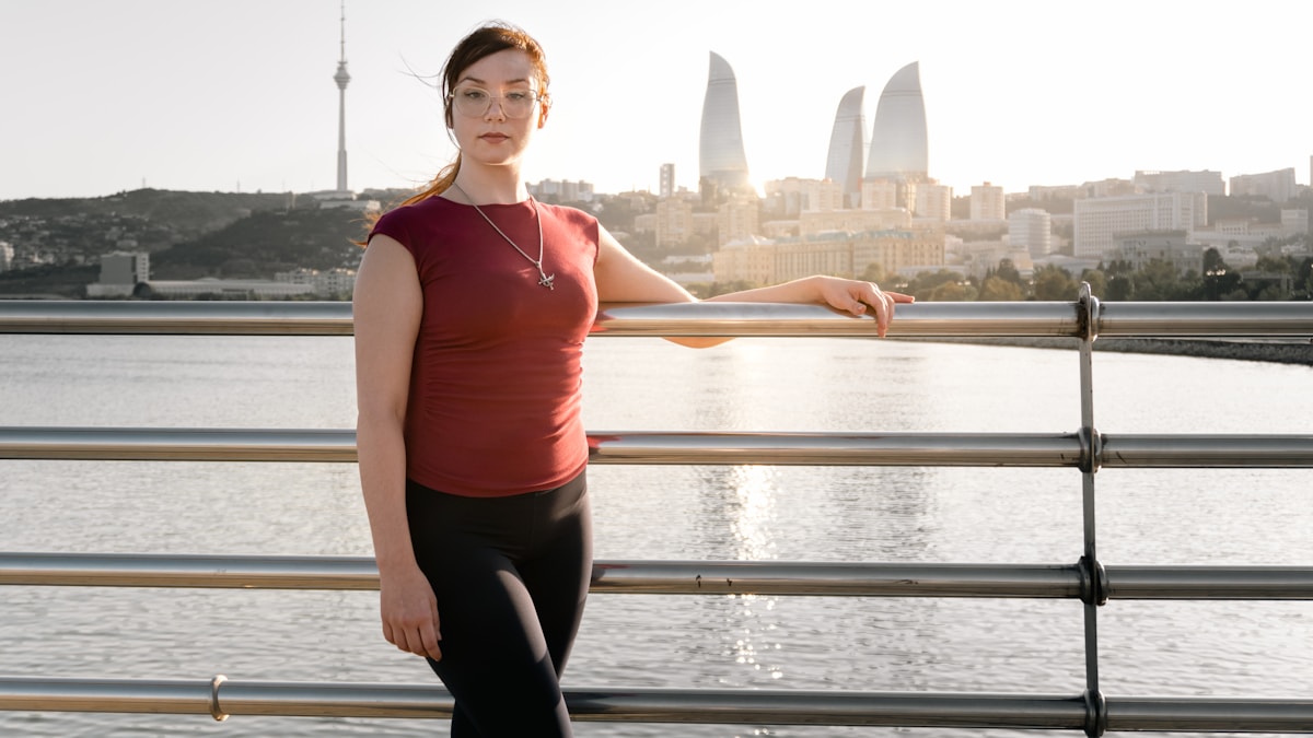Woman standing tall by a railing with a city skyline behind her
