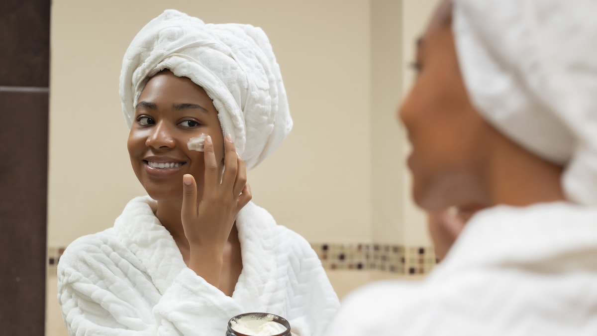 Woman applying moisturizer with a towel on her head