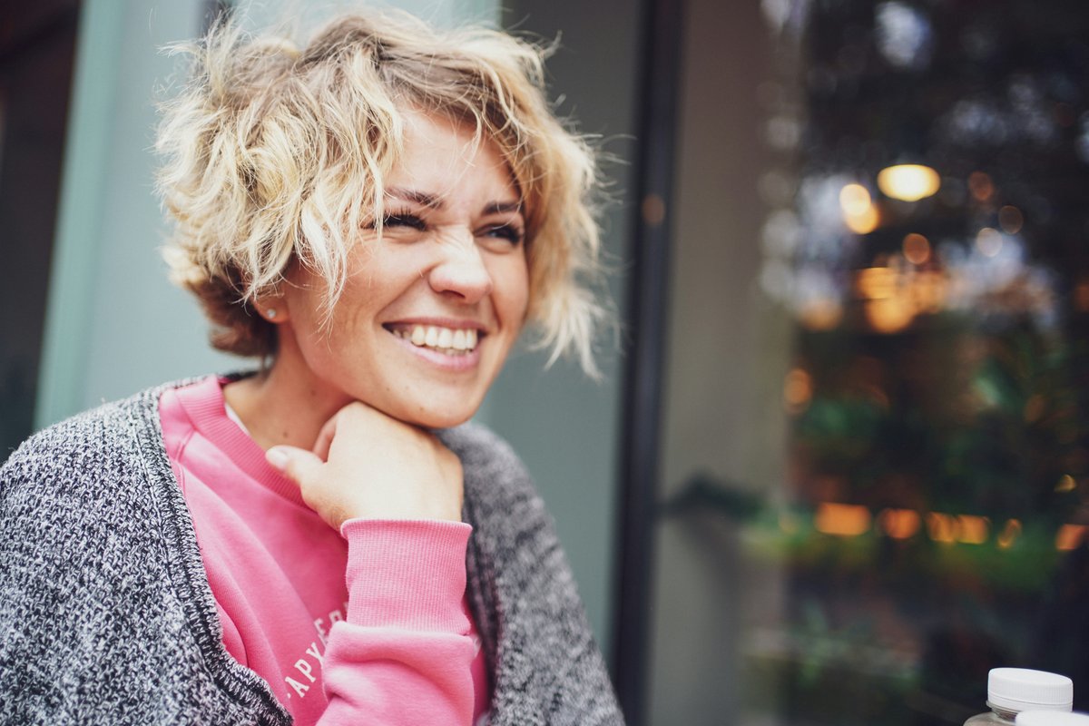 Smiling woman in a pink shirt and grey cardigan