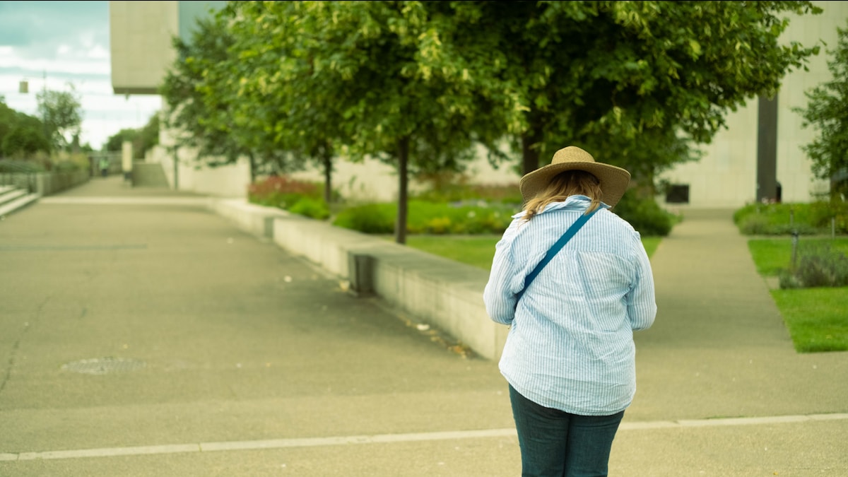 Woman in a hat walking along a paved path